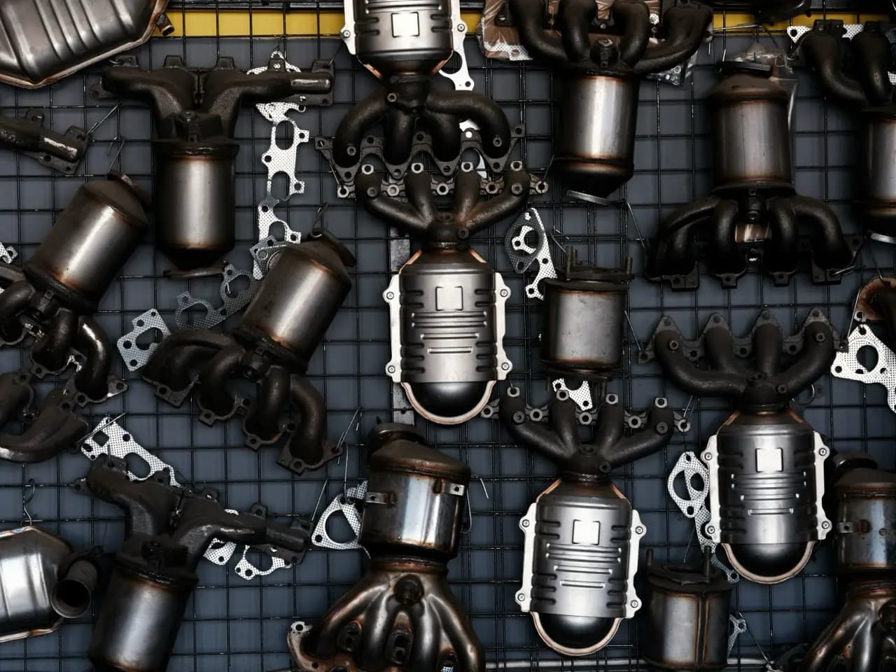 Metallgitterwand, an der viele Abgaskrümmer mit Katalysatoren hängen